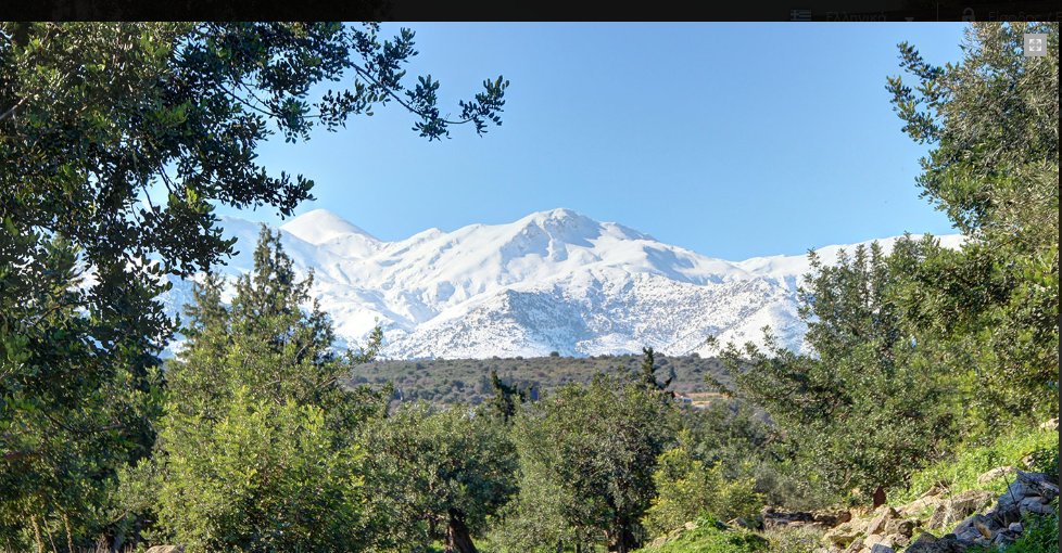 Snow-capped peaks of the White Mountains in Crete, seen through olive trees on a clear winter day.αι 